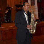 A man in a suit and tie playing the saxophone.