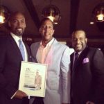 Three men in suits and ties holding a plaque.